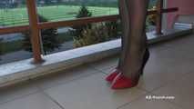 Dipping classic red high heels on balcony