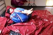 Simone tied and gagged by Sophie in bed wearing a blue and black shiny PVC sauna suit (Pics)