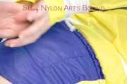 Mara tied and gagged with ropes and cloth gag on a sofa wearing a sexy blue shiny nylon shorts and a yellow/black oldschool rain jacket (Pics)