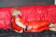 Pia tied and gagged with nack ties on a bed wearing a sexy red shiny nylon rainwear catsuit (Pics)