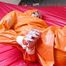 Pia tied and gagged in bed in a orange rainsuit and a red gag (Pics)