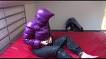 Jill ties and gagges herself sitting on a bed wearing a sexy shiny nylon rain pants and a purple down jacket (Video)