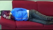 Mara tied, gagged and hooded on a sofa wearing a shiny blue rainjacket and a black rain pants  (Video)