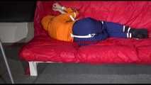 Lucy wearing a blue rain pants and an orange rain jacket being tied and gagged with belts on a sofa (Video)