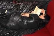 Lucy wearing a supersexy black rain catsuit posing and lolling on a sofa (Pics)