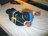 Dark-haired archive girl tied, gagged and hooded on a bed wearing a shiny nylon shorts (Pics)
