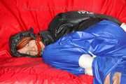 Sonja wearing a sexy blue shiny nylon raver pants and a black down jacket being tied and gagged with ropes on a sofa (Pics)