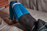 Tied arms and suspended legs in blue leggings