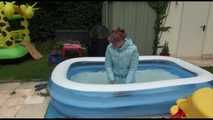 Watching sexy Mara wearing a blue rain pants and a lightblue down coat playing with water in the pool (Video)