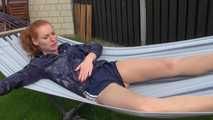 Watching our new modell RONJA wearing a sexy darkblue shiny nylon shorts and a darkblue rainjacket walking through a garden lolling in a hammock enjoying the cloth she wear (Video)