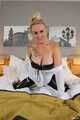 Busty blonde Frida posing in white shirt, leather corsage and black glossy leggins on bed