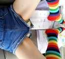 Emma with rainbow socks, a denim shortall and a pile of diapers