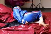 Simone tied and gagged by Sophie in bed wearing a blue and black shiny PVC sauna suit (Pics)