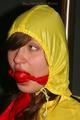 Alina tied and gagged to a pole in nylon shorts and yellow cagoule