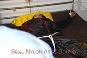 Lucy tied and gagged in a bed wearing a black shiny nylon downwear combination (Pics)