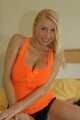 Busty blonde Anna in a orange top and hotpants on bed with oil