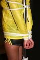 Alina tied and gagged to a pole in nylon shorts and yellow cagoule